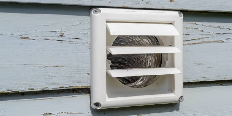 A dryer vent viewed from the outside of a house.